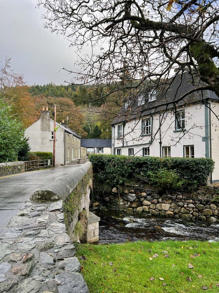 In this image you can see several village buildings in the Village of Glendalough in the Wickow Mountains, Ireland. The foreground shows an old bridge with the river running below.