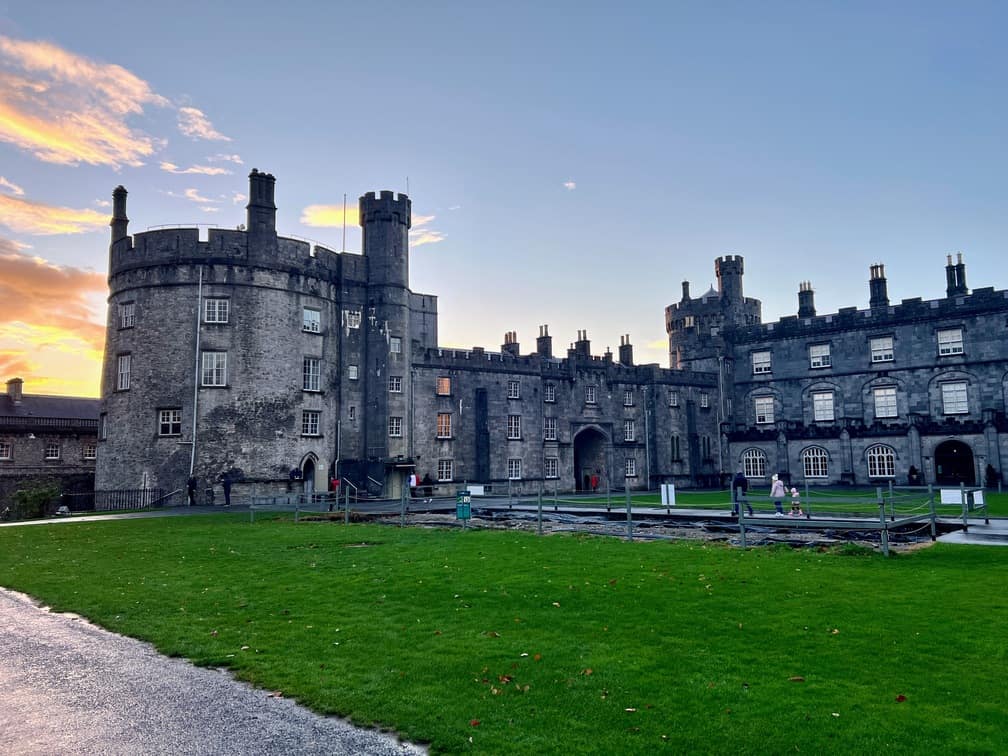 In this image Killkenny Castle in Ireland is visible at sunset.