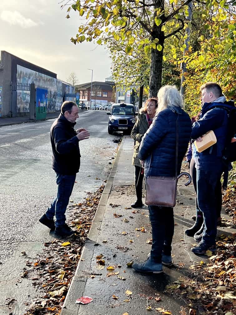 A tour guide speaks to a group of tourists in front of the political murals located in Belfast, Northern Ireland.