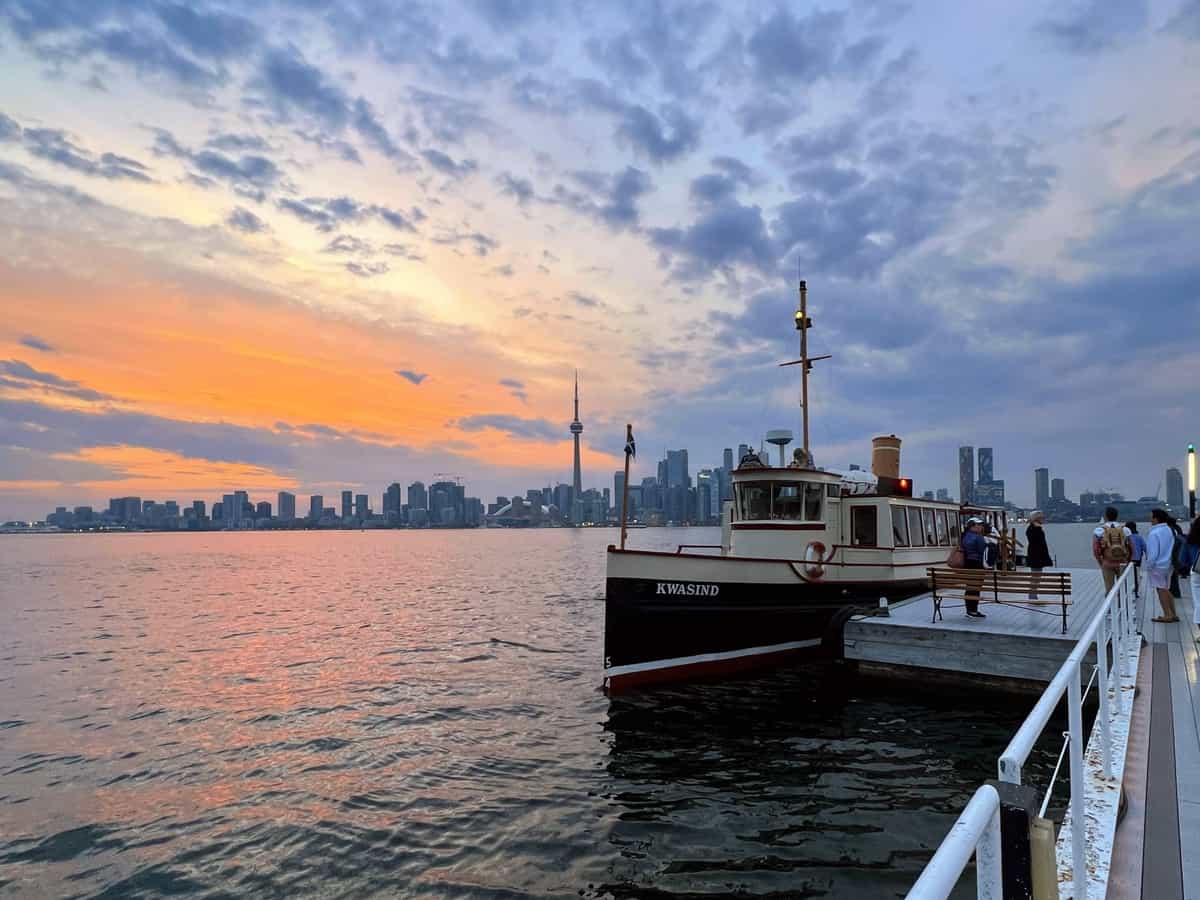 Small ferry on Lake Ontario with the Toronto skyline at sunset behind the boat, resulting in a beautiful sunset view of the Toronto skyline at sunset. 