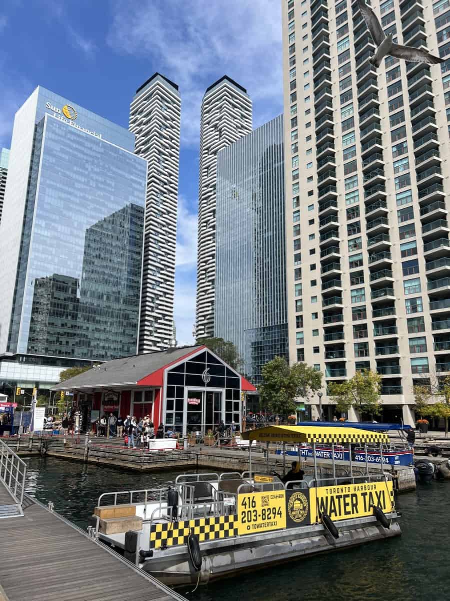 Water Taxi in the water at Harbourfront with tall buildings towering over the boats.