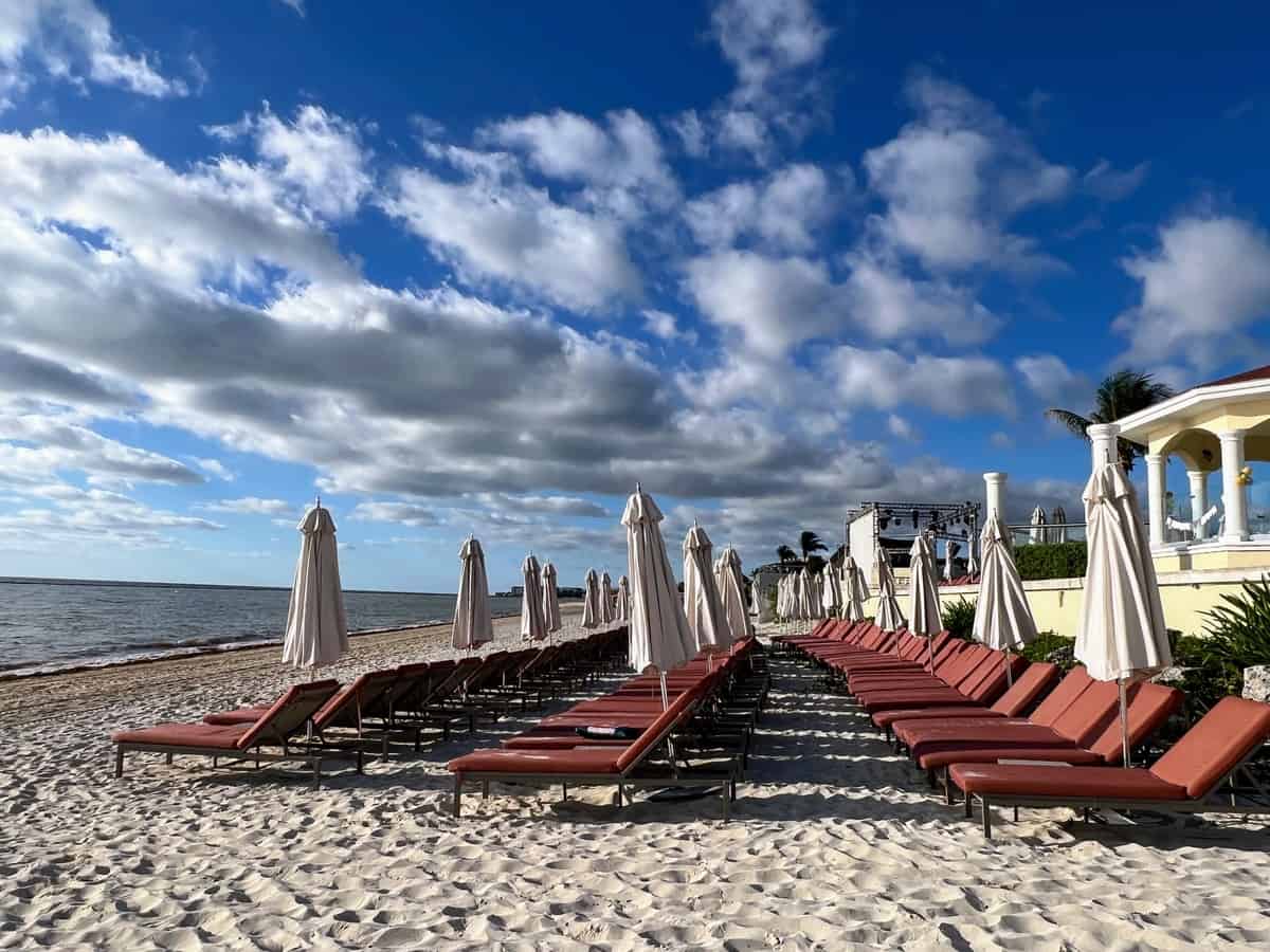 Rows of beach loungers with umbrellas line the beach at Moon Palace Cancun Nizuc on a sunny day.