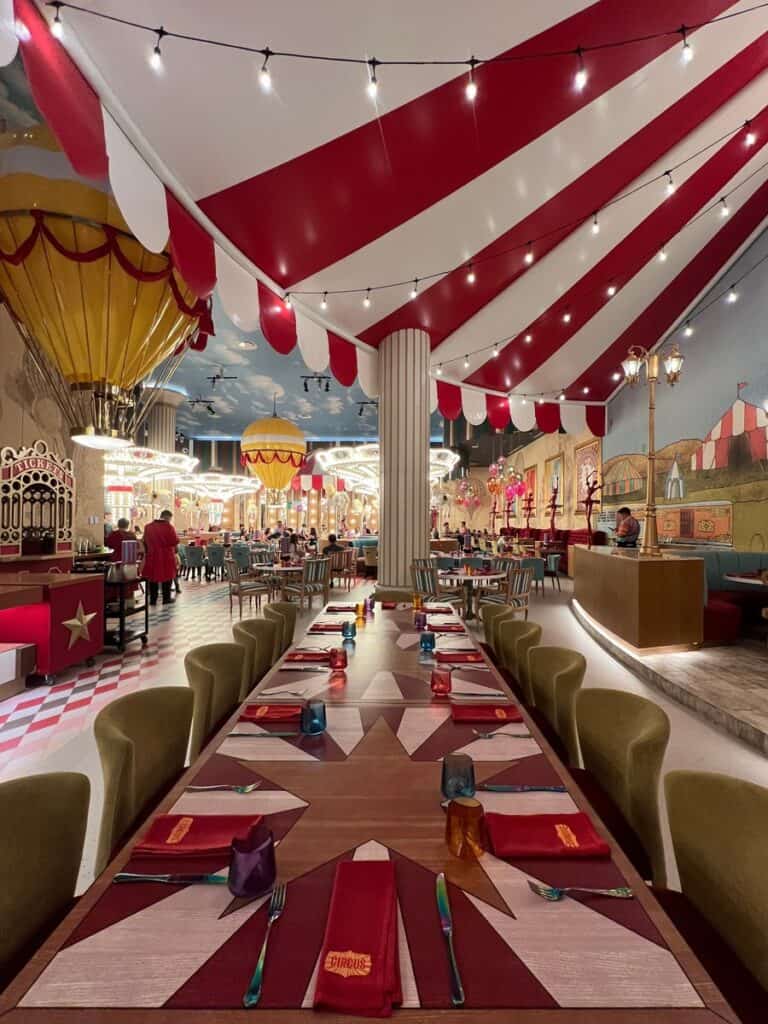 Long table is set up in a circus themed restaurant at the Grand at Moon Palace. Restaurant is empty. The table is under the read and white big top and hot air balloons can be seen in the background.