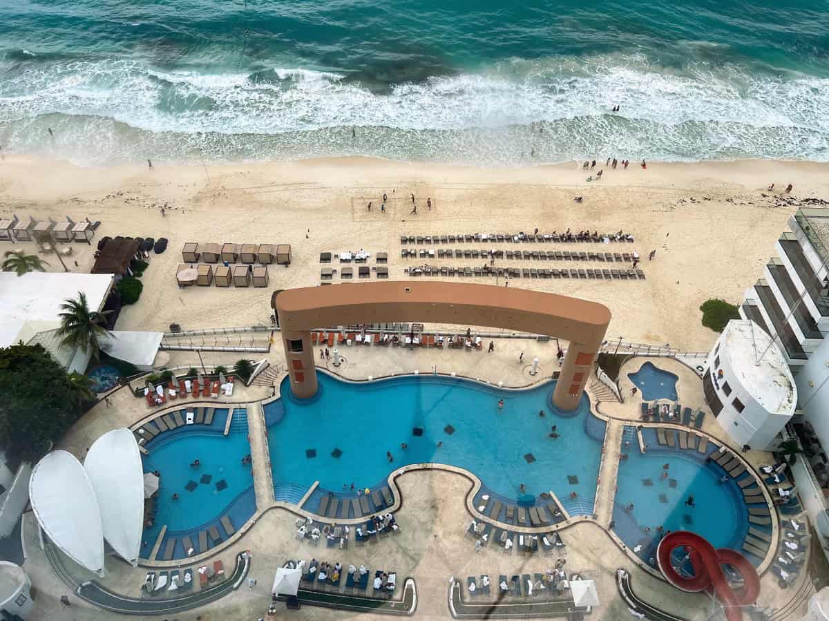 Aerial view of the Beach Palace Resort’s swimming pool and beach area. The pool’s unique shape and the beach’s golden sand create a luxurious setting where guests can swim or sunbathe while enjoying the oceanfront.