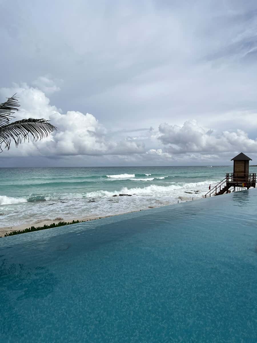 Infinity pool at Sun Palace Resort with crystal-clear water blending seamlessly into the horizon of the Caribbean Sea. Waves crash on the beach below, providing a perfect backdrop for relaxation and ocean views.