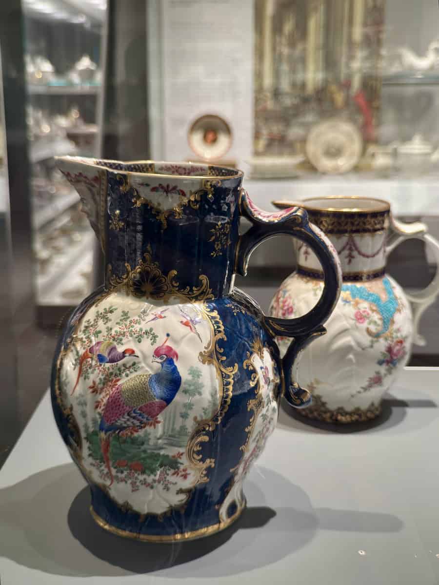 Close-up of ornate ceramic pitchers with peacock and floral designs, displayed at the Gardiner Museum in Toronto, known for its world-class ceramics collection.