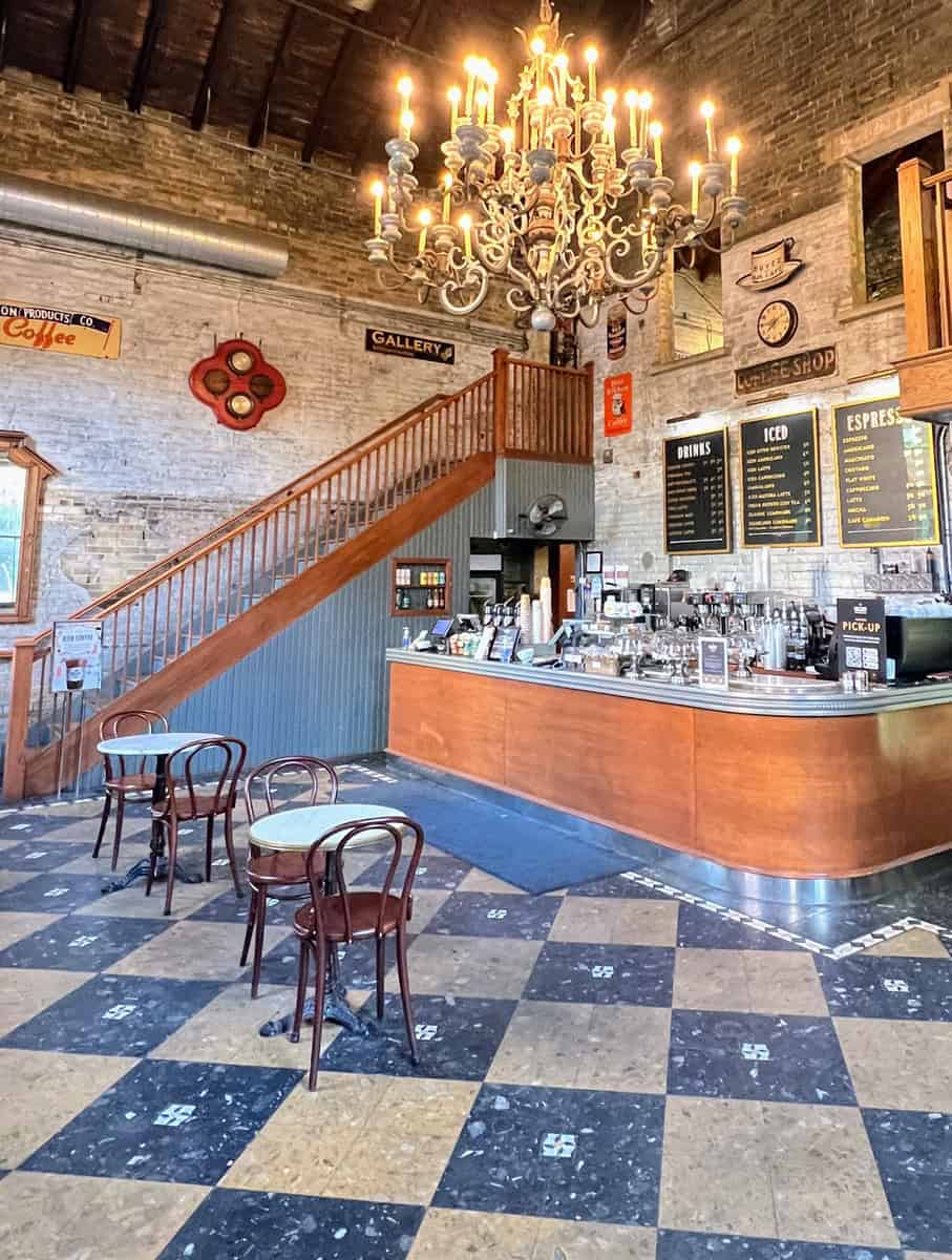 Interior of Balzac’s Coffee in the Distillery District Toronto, showcasing vintage charm with a grand chandelier, cozy seating, and a rustic café counter beneath high ceilings.