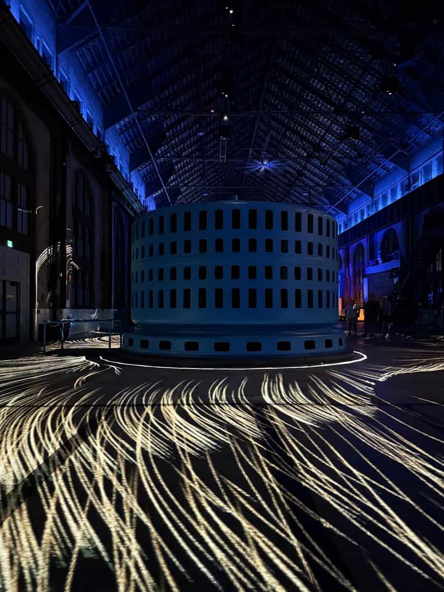 Inside the Niagara Parks Power Station generator hall, golden light patterns swirl across the floor during the nighttime Currents show.