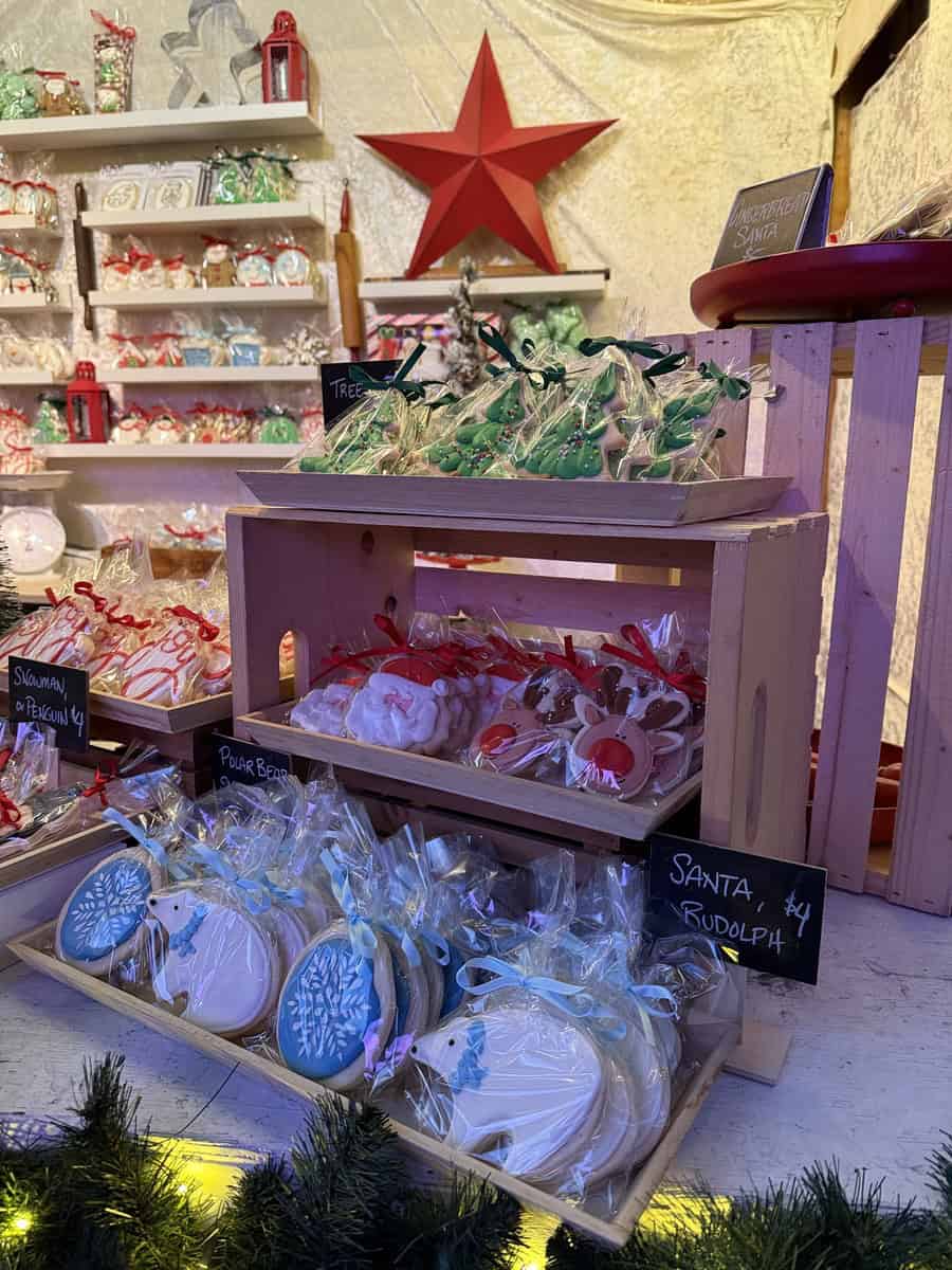 Holiday cookies for sale at a vendor booth inside the Distillery District winter village Christmas market in Toronto, including Santa, Rudolph, and polar bear designs.