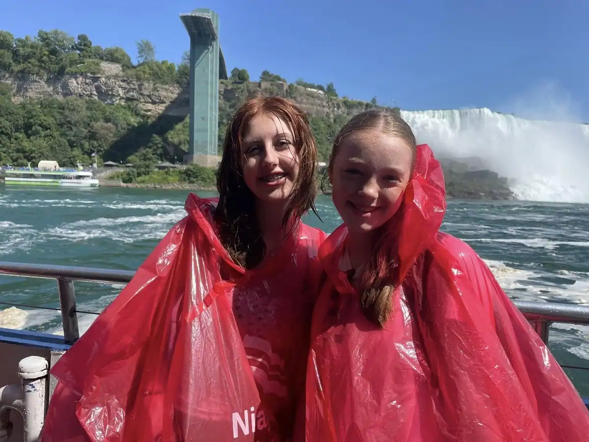 Two girls in red ponchos enjoying the Niagara Falls Canada boat ride with Horseshoe Falls in the background during a Niagara City Cruises tour.