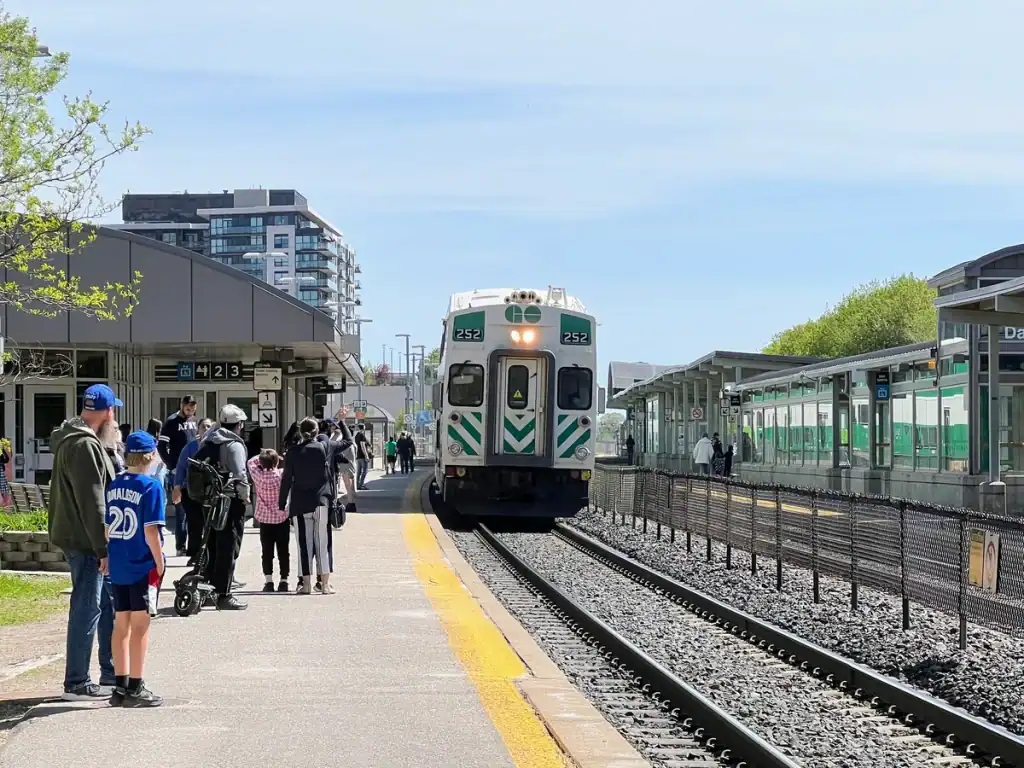 Passengers wait on the platform as a GO Train arrives at Danforth Station, showing a key part of public transport in Toronto for tourists traveling beyond the downtown core.