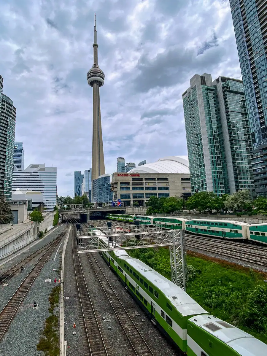 Multiple GO Trains arriving at Union Station in downtown Toronto with the CN Tower in the background, showing one of the best ways for getting around Toronto.