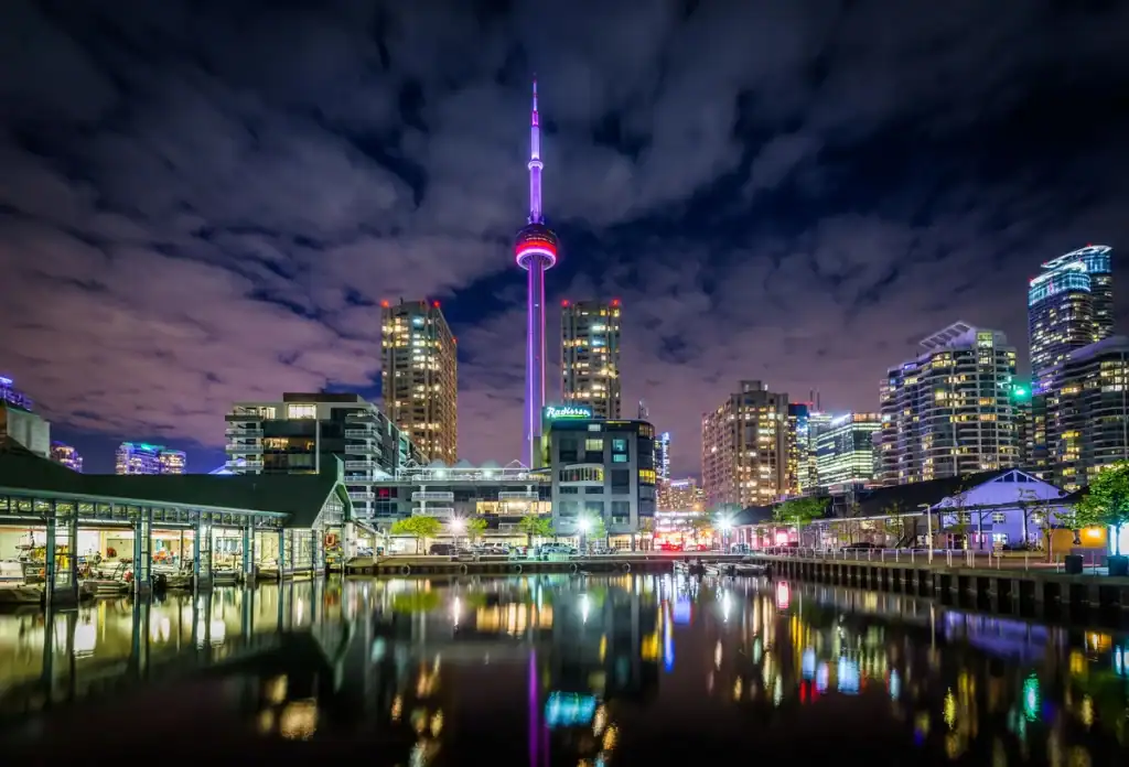 Toronto Skyline at night with views of the CN Tower and the Toronto waterfront with lights reflected in Lake Ontario.