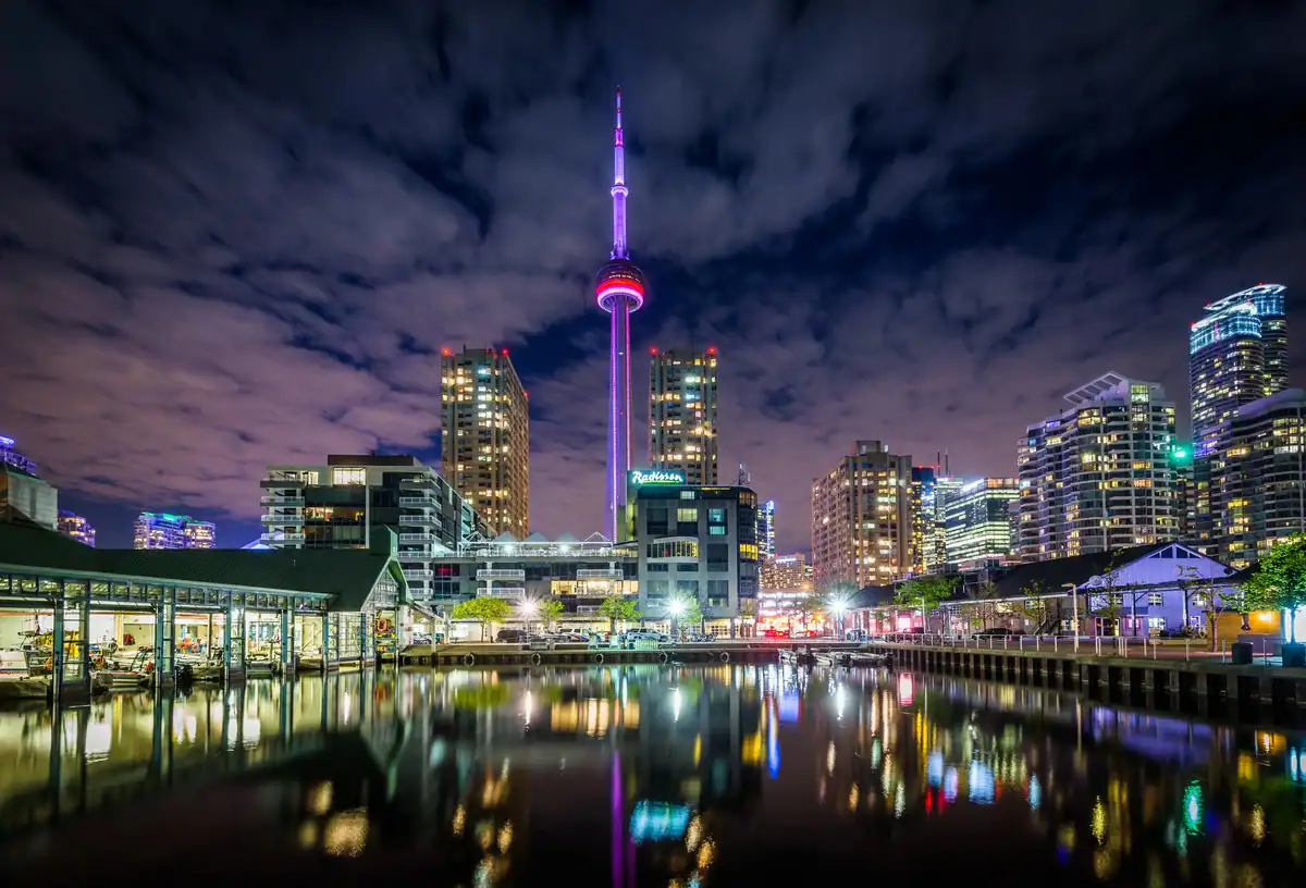 Toronto Skyline at night with views of the CN Tower and the Toronto waterfront with lights reflected in Lake Ontario.