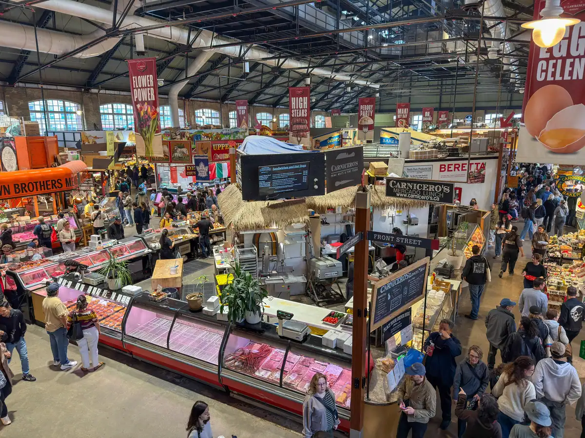 Overhead view of the main south market at St Lawrence Market with views of various vendors and many people walking between the food vendors.