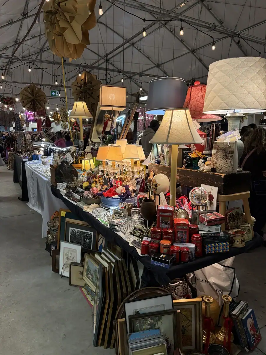 Antique vendor stall with vintage lamps, maps, prints, china, and various knick knacks at the indoor Vintage Market located in the temporary tent at St Lawrence Market Toronto.