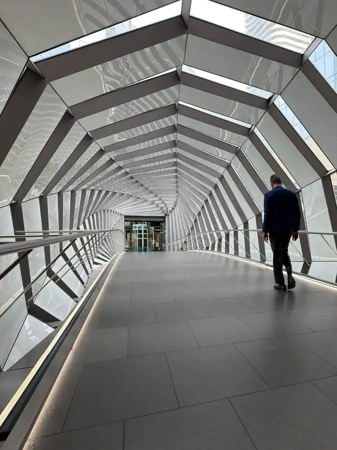 A business man in a suit walks through a bridge over Queen Street and into the Eaton Centre Shopping Mall in downtown Toronto. The bridge is part of the PATH system in Toronto.