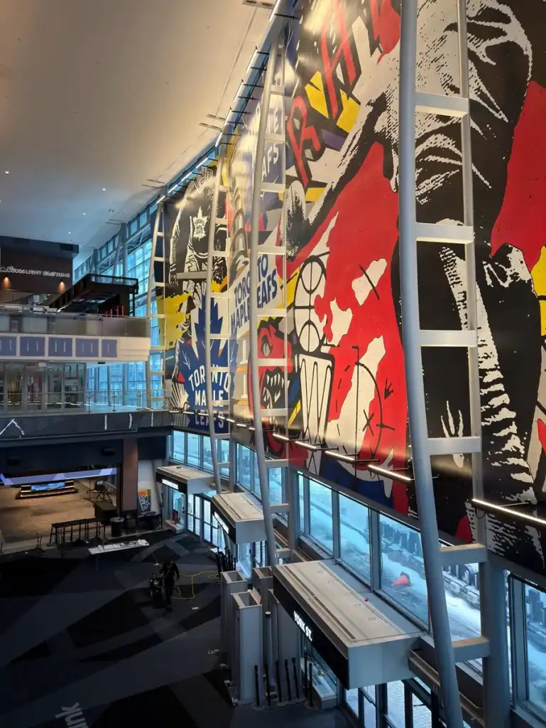 The inside of Scotiabank Area viewable from the PATH. Colourful murals can be seen with images of the Maple Leaf and Raptors logos.