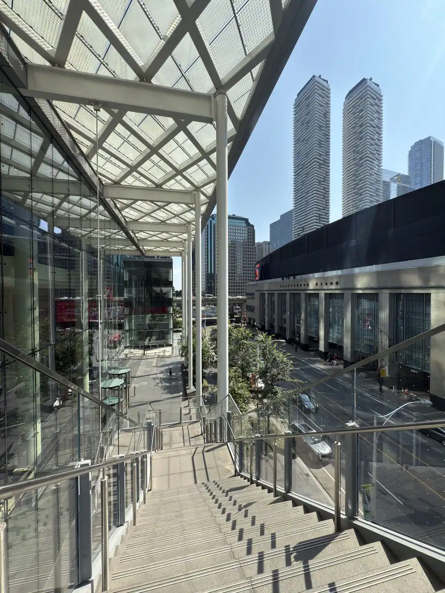 Stairs lead down from the roof of the CIBC building which is accessible as part of the PATH network. The Scotia Bank Arena is across the street. Skyscrapers are in the distance.