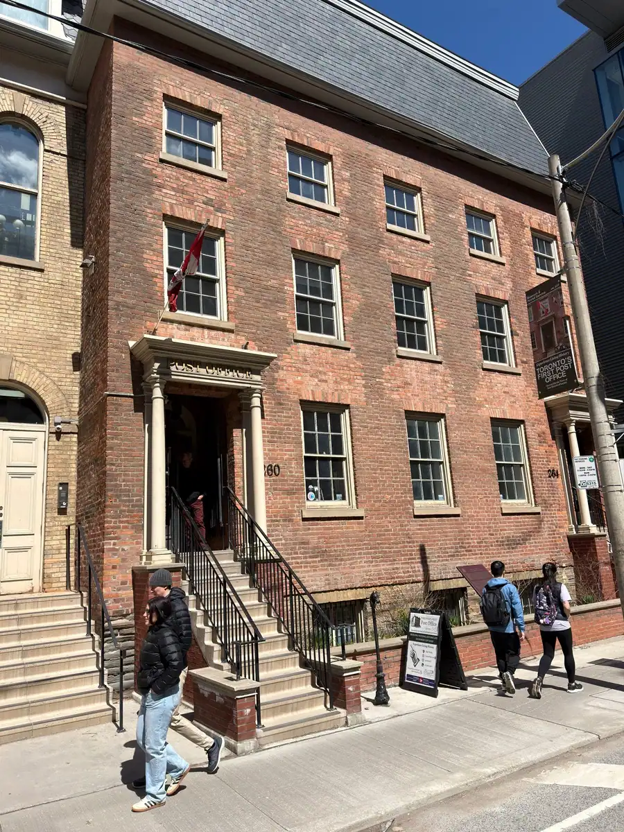Entrance to Toronto's First Post Office a free historic museum and working post office in downtown Toronto. People are walking by the entrance on a sunny spring day.
