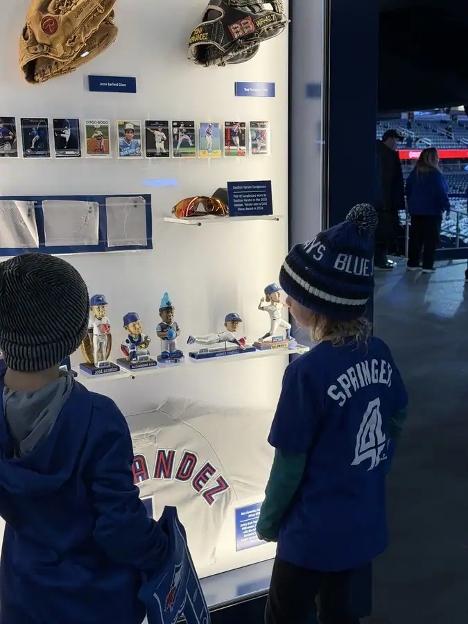 Two young Blue Jays fans admire Jays memorabilia include bobbleheads, baseball gloves, and baseball cards inside Toronto's Rogers Centre.