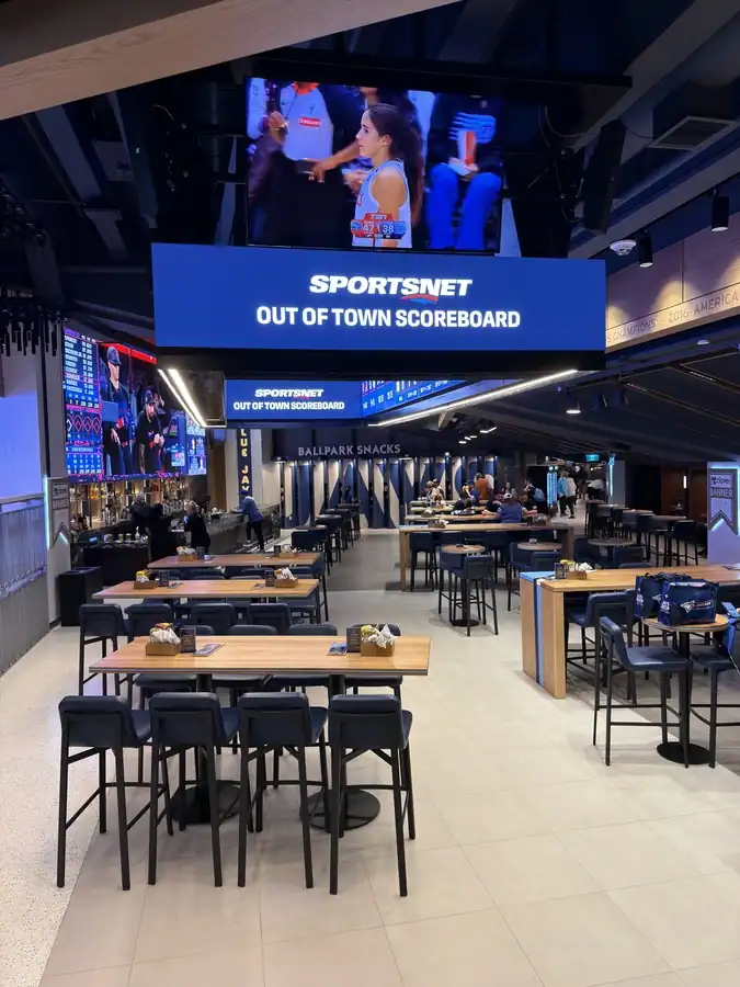 A large screen displays the Blue Jays baseball game over a bar and restaurant in the banner club at the Rogers Centre.