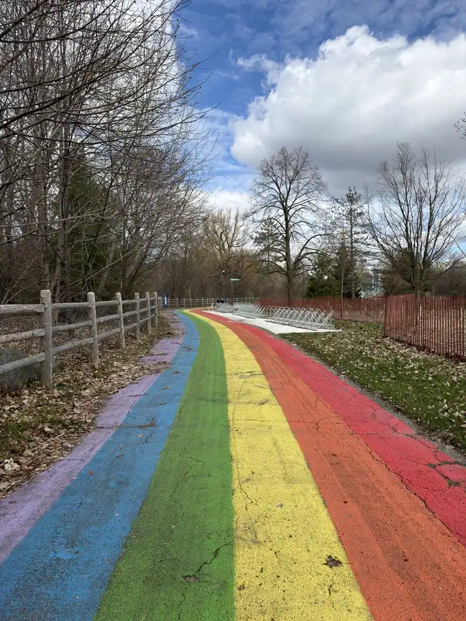 A biking path is painted in the colours of the rainbow including purple, blue, green, yellow, orange and red. The path is located on the Toronto Islands at Hanlan's Beach.