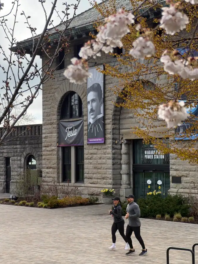 Runners run in front of the historic Niagara Power Station surrounded by spring cherry blossoms.