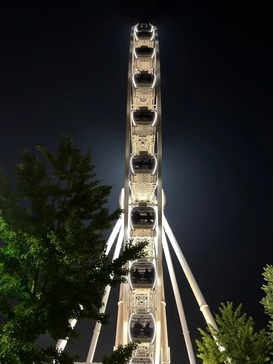 Enclosed gondolas from the ferris wheel in Niagara Falls are lit up with LED lights in the evening. The SkyWheel towers over Clifton Hill.