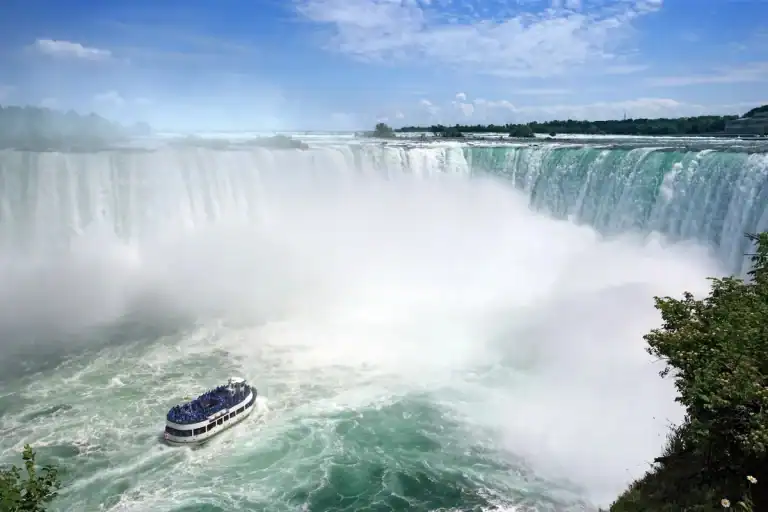 Niagara's boat cruise Maid of the Mist heads to the base of the incredible Horseshoe Falls in Niagara Falls Canada on a summer day.